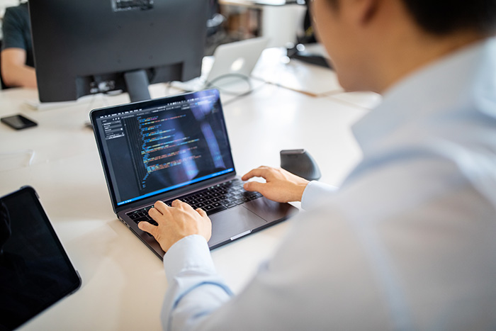 En inte igenkänningsbar man sitter framför en laptop på ett kontor