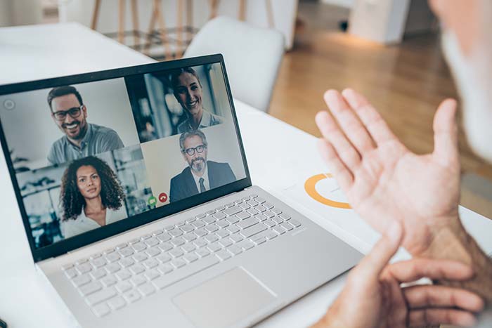 En inte igenkänningsbar man som har ett videomöte på sin laptop i sitt hem